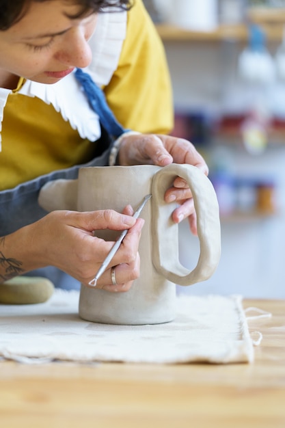 陶磁器のスタジオまたはワークショップで粘土の瓶をモデリングおよび成形する陶器店の中小企業のプロセス