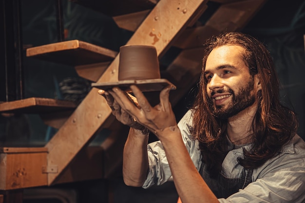 Pottery worker proud with work handcraft making artisan male pot maker with hand made clay cup