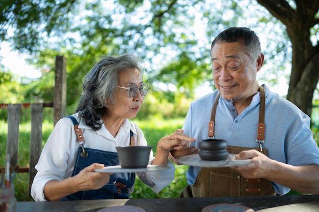 In the pottery workshop an Asian retired couple is engaged in pottery making and clay painting