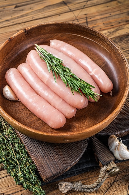 Poultry raw sausages in a wooden plate with herbs