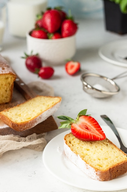 Pound or loaf cake with strawberry and mint on wooden board. 