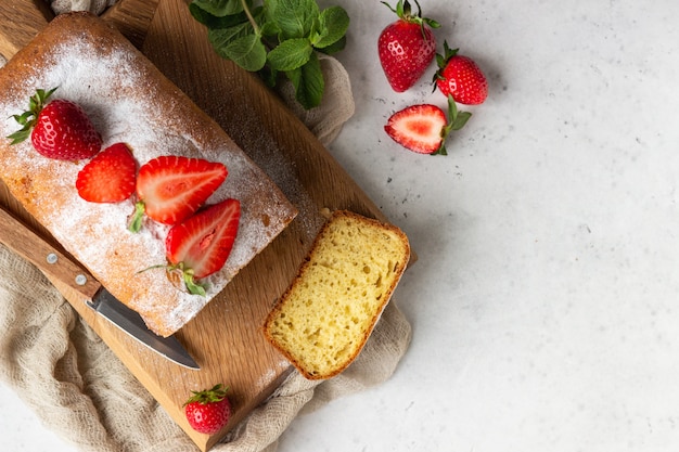 Pound or loaf cake with strawberry and mint on wooden board. 