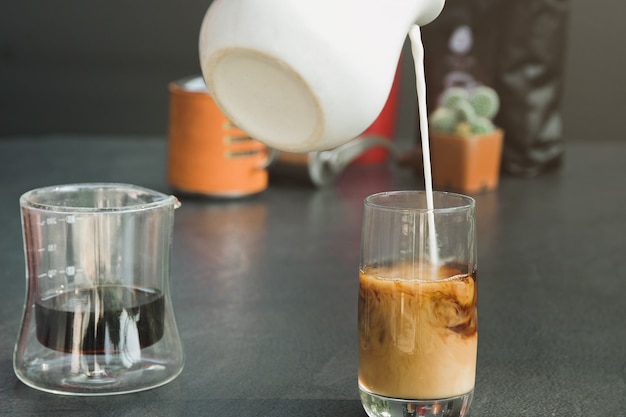 Foto versare il latte fresco in una tazza di caffè nero.