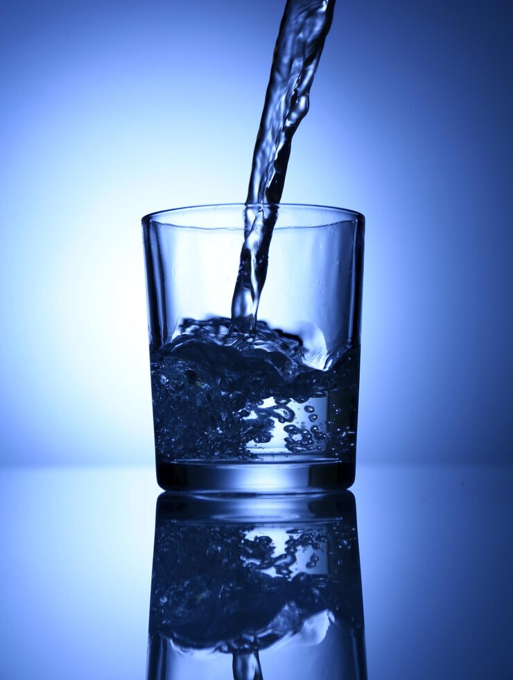 फोटो pour water from pitcher into glass on dark blue background