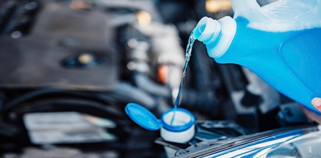 Pouring antifreeze filling a windshield washer tank with an\
antifreeze in winter cold weather