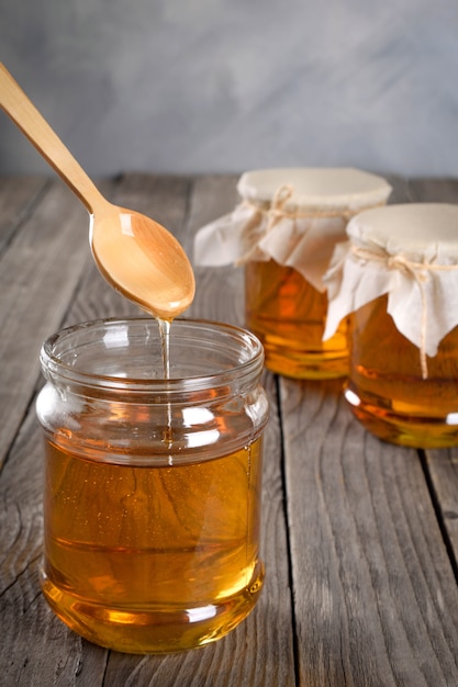 Photo pouring aromatic honey into jar, closeup.