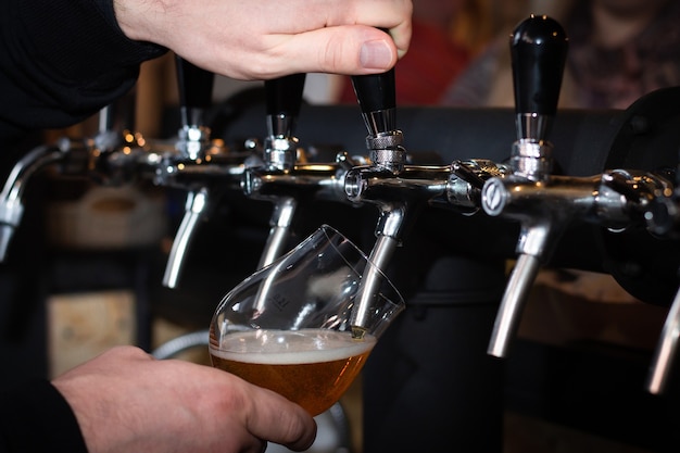 Photo pouring beer from silvery bar tap in a pub