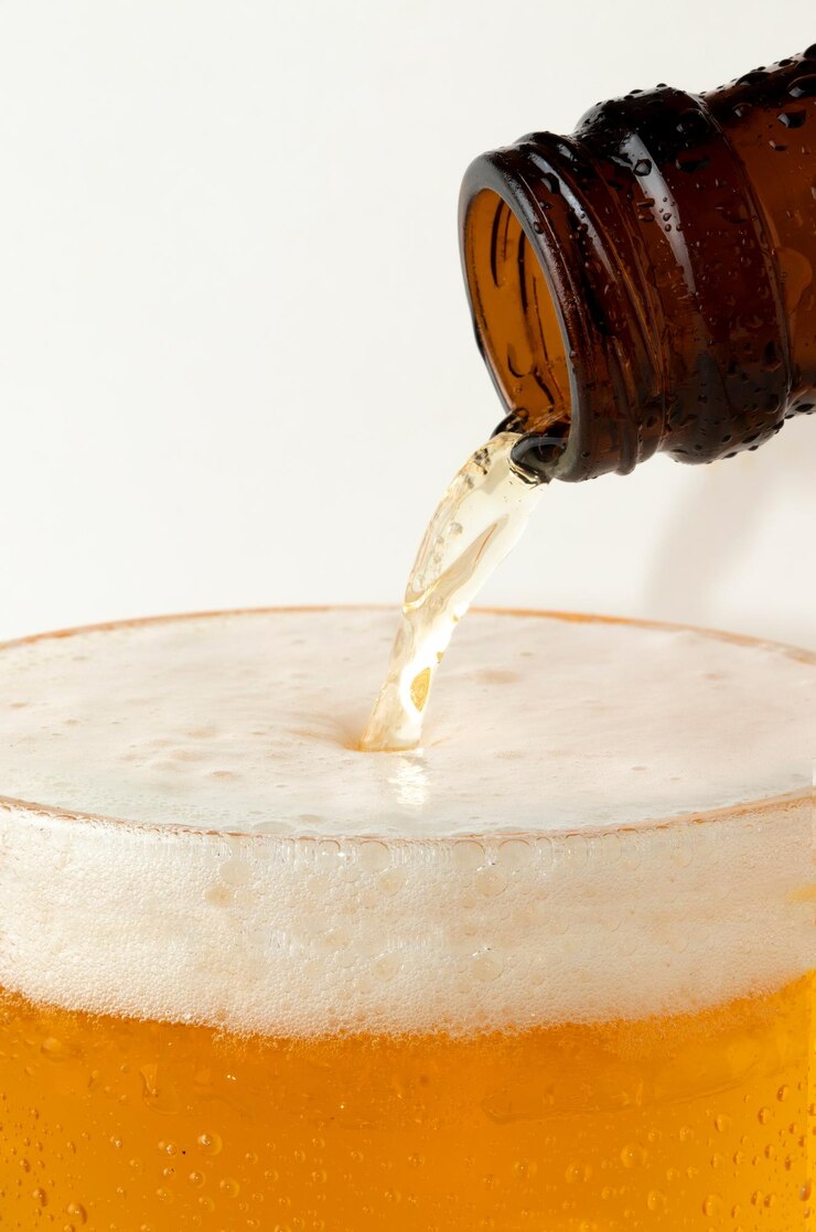 白い背景で隔離のガラス カップにビールを注ぐ