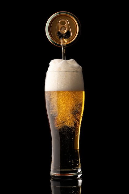 Pouring beer into glass isolated on black background