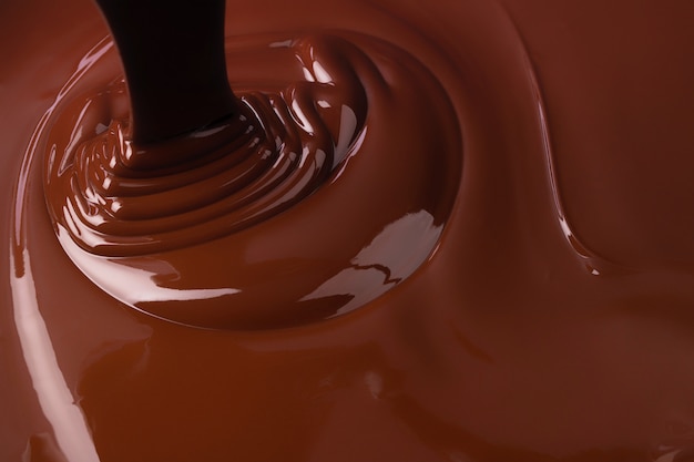 Versare lo sfondo al cioccolato. sciroppo di cacao che scorre formando increspature