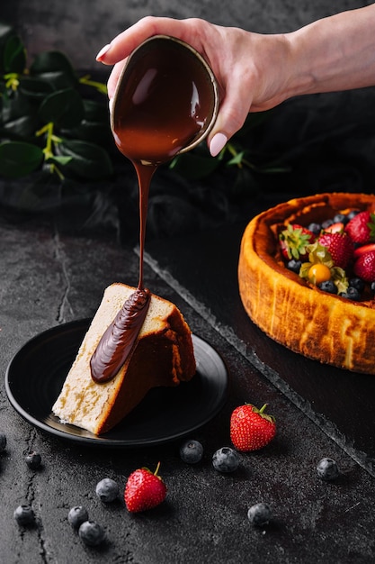 Pouring chocolate on delicious cheesecake and berries