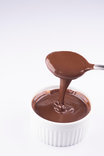 Заливка шоколадно-орехового крема ложкой на белом фоне