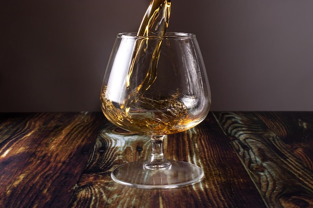 Pouring cognac into the glass and spilling past the glass