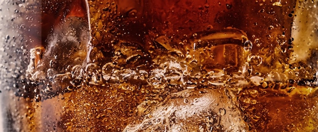 Pouring of Cola and Ice Cola soda and ice splashing fizzing or floating up to top of surface