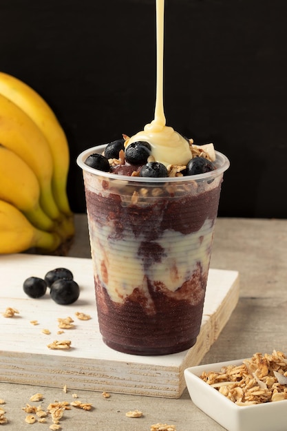 Pouring condensed milk in a acai cup. Selective focus