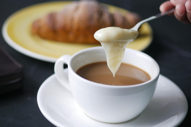 Pouring condensed milk in cup of tea