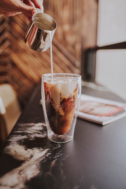 Pouring cream in coffee in rocks glass