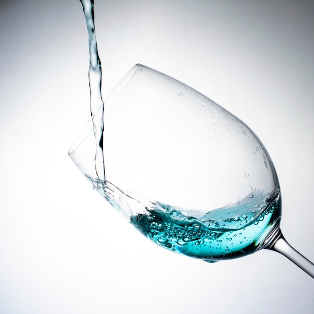 Pouring a drink into the wine glass on a soft grey