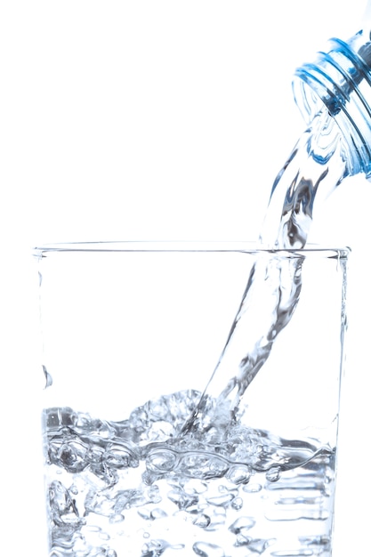 Versare acqua potabile da bottiglia in vetro su sfondo bianco.