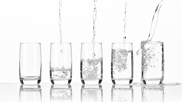 Pouring fresh mineral water into five glasses standing on a glass table on a light wall