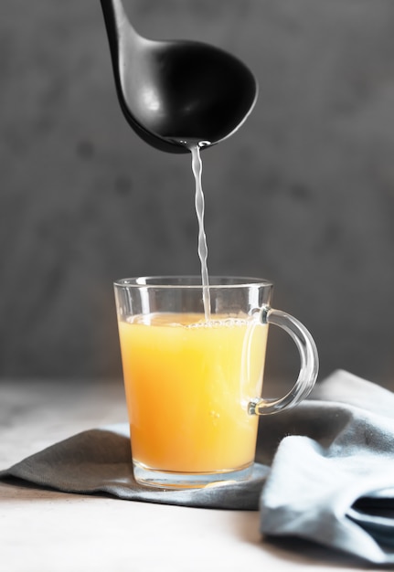 Pouring Homemade Beef Bone Broth in Glasses on a gray concrete space