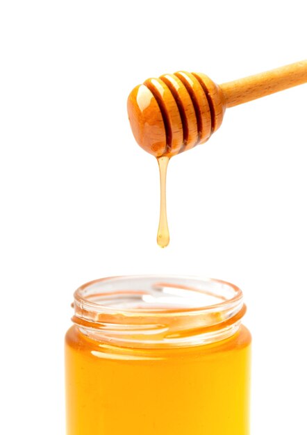 Pouring honey from a dipper into a jar isolated