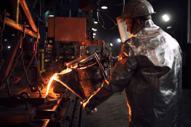 Pouring hot iron in foundry, industrial steel production and casting.