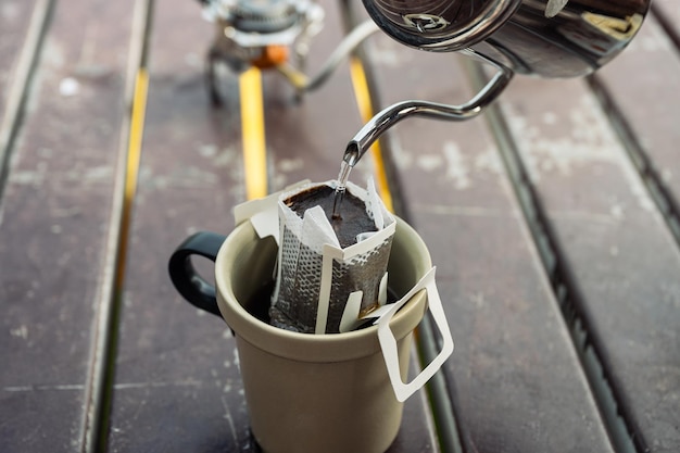 Pouring hot water from the kettle into filter ground coffee on a cup. Making drip coffee in the morning