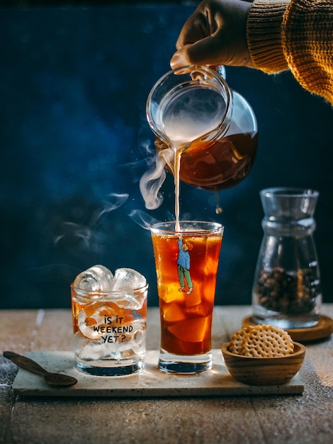 Pouring Iced Coffee in transparant glass. Dark mood photography