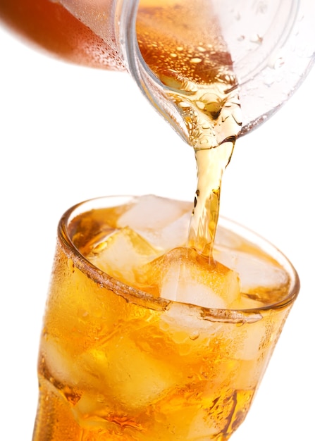 Pouring iced tea into glass with ice from jar isolated on white background