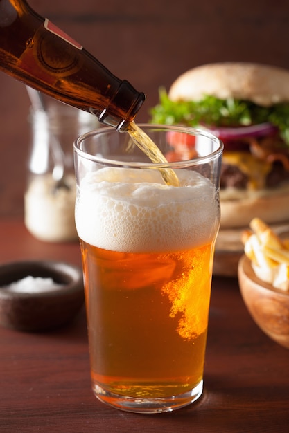 Versare la birra chiara india in vetro pinta e fast food