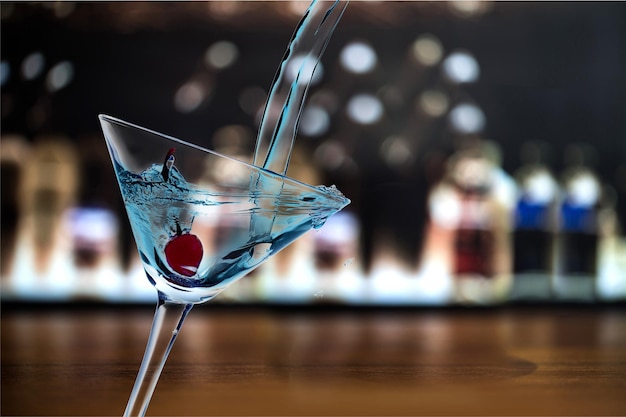 Pouring Martini cocktail in glass  on blurred background