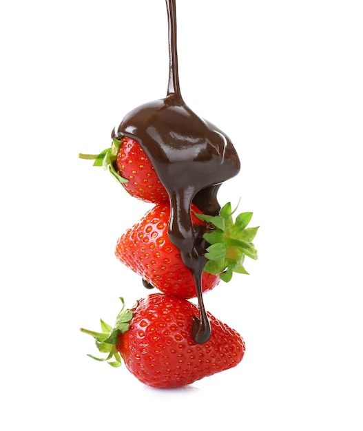 Pouring melted chocolate on juicy strawberries on white background