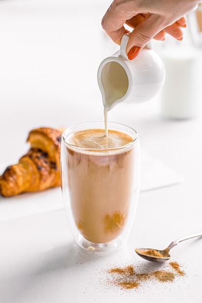 Pouring milk in a glass of coffee latte