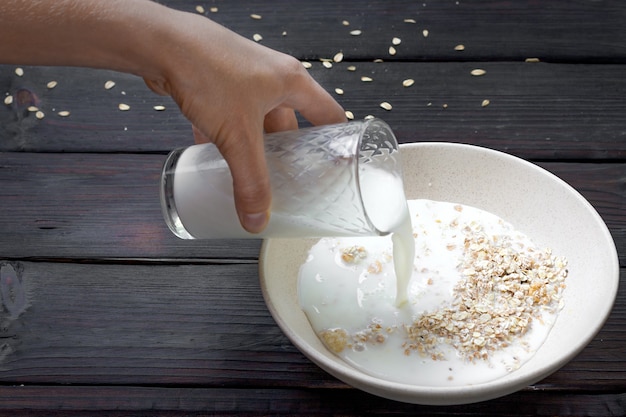 Foto versare il latte in una ciotola di farina d'avena su un tavolo di legno