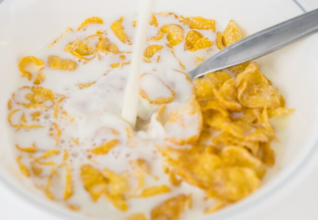 Photo pouring milk into corn flake cereal breakfast