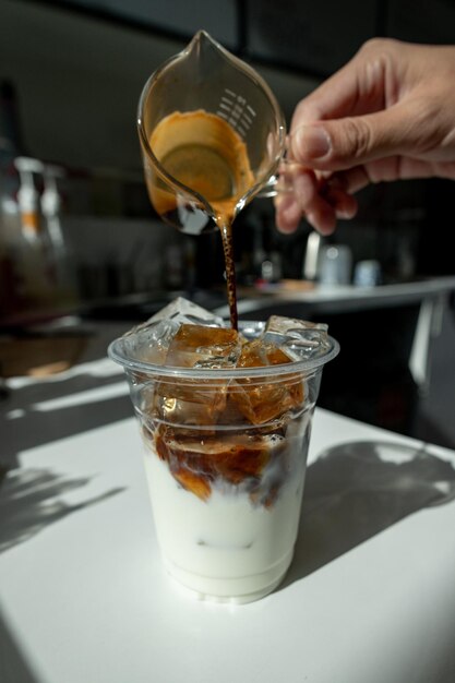 Pouring milk into a glass of ice coffee in a cafe