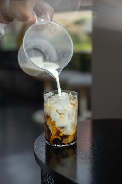Pouring milk into a glass of iced coffee