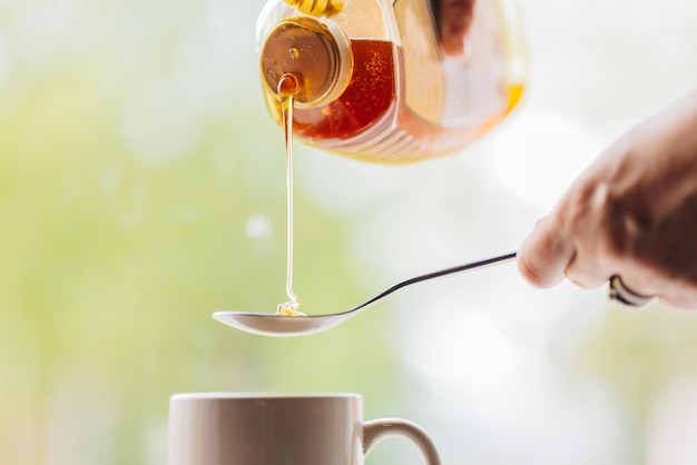 Photo pouring natural honey into spoon to put in to morning tea