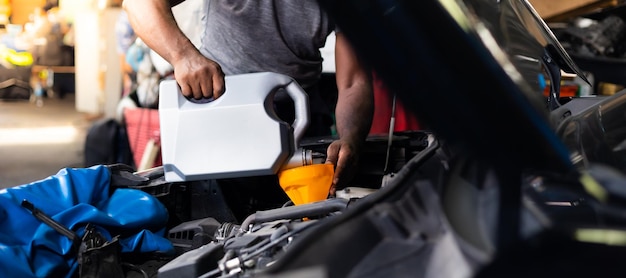 Pouring oil to car engine Closue up male mechanic hand working and service in Car Service station