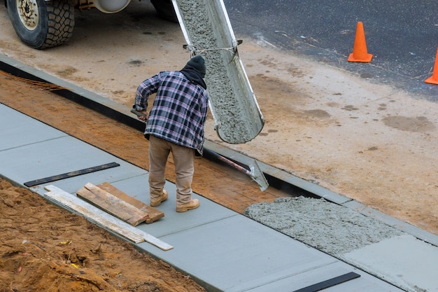 Заливка в процессе заливки бетонного цемента на недавно проложенный тротуар