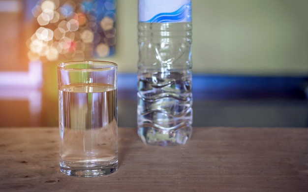 Pouring purified fresh drink water from bottle on glass table background