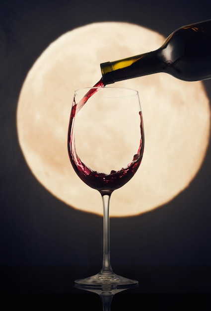 Pouring red wine against the moon