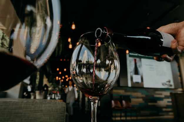 Pouring red wine from bottle into the wineglass