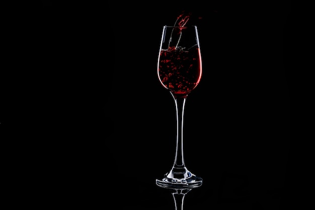 Лить красное вино в стекле на темноте. Изолированный силуэт