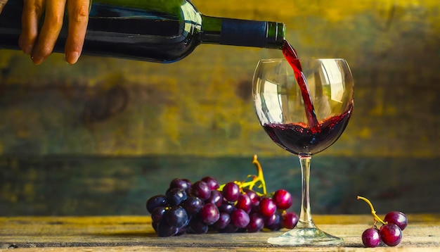 Pouring red wine into the glass against rustic background Pour alcohol winery concept