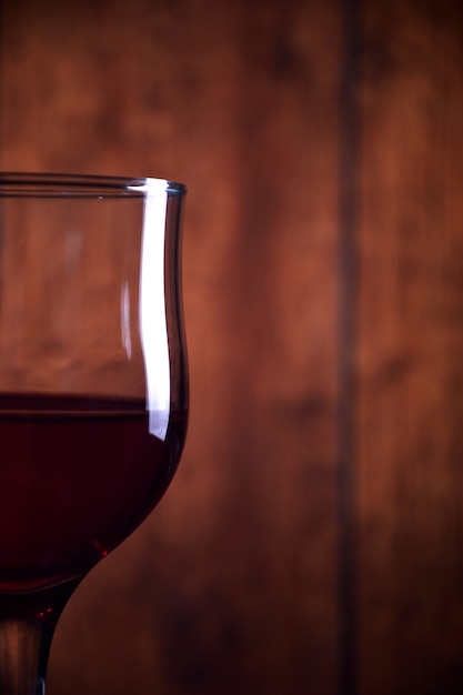 Pouring red wine into the glass against wooden rustic background