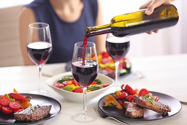 Photo pouring red wine into glass at lunch time