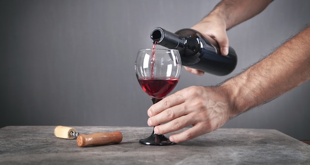 Pouring red wine into the glass.