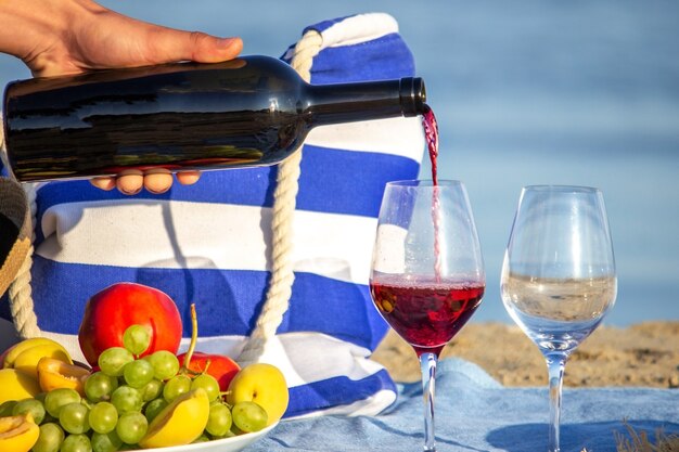 Pouring red wine into glasses, overlooking the sea, picnic by the sea. Nature. Selective focus